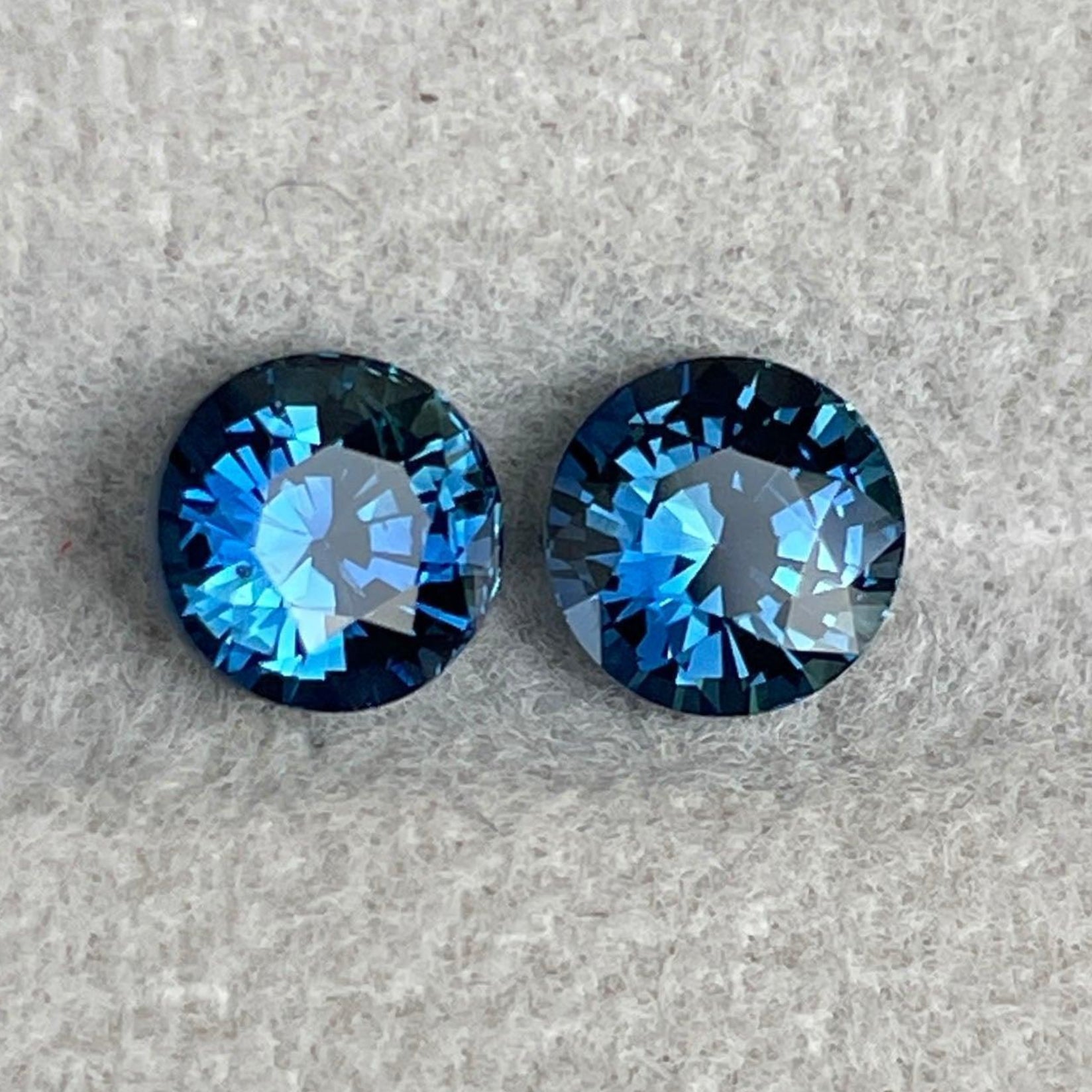 Pair of blue-green teal sapphire round cut gemstones from NASHGEMS, ideal for anniversary, Mother's Day, or engagement jewelry.