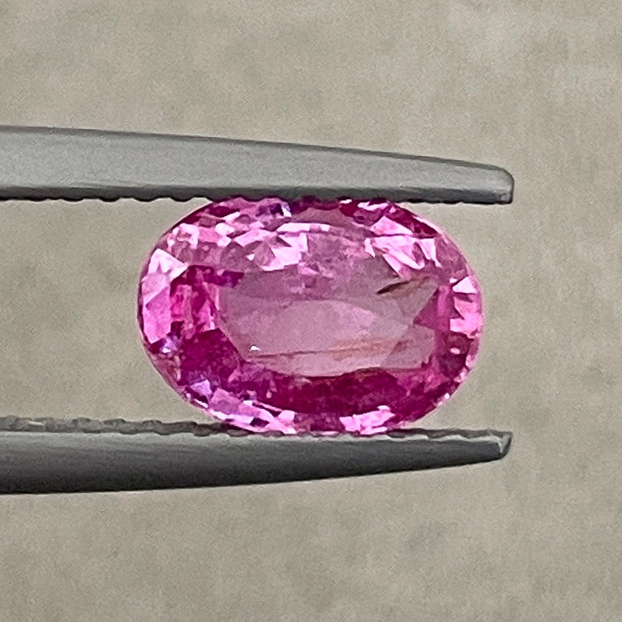 Natural pink sapphire loose gemstone, 1.65 Ct oval cut by NASHGEMS, showcasing vibrant pink color and polished surface.