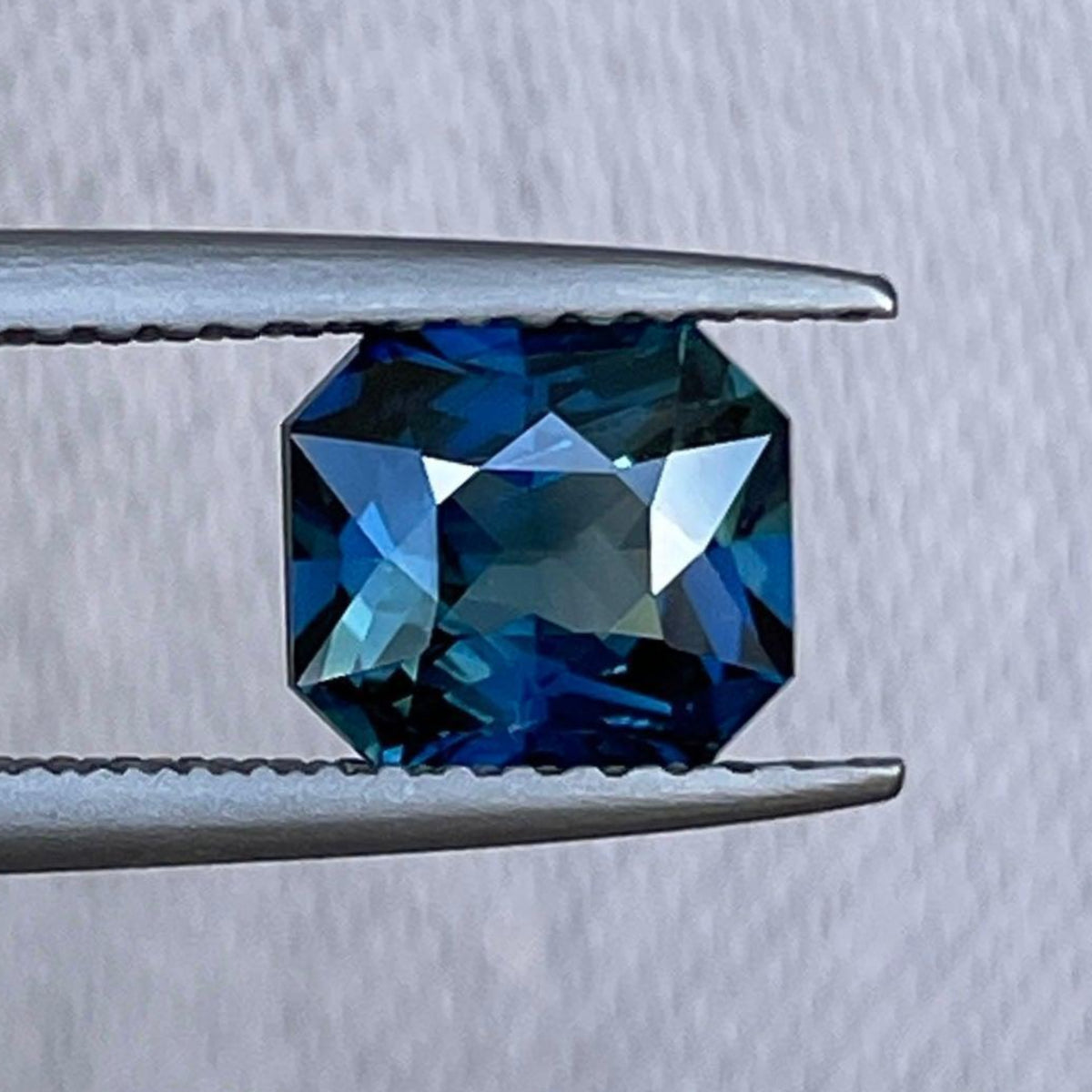 Teal sapphire precious stone with radiant cut, 1.54 carats, from NASHGEMS, ideal for engagement rings or jewelry designs.
