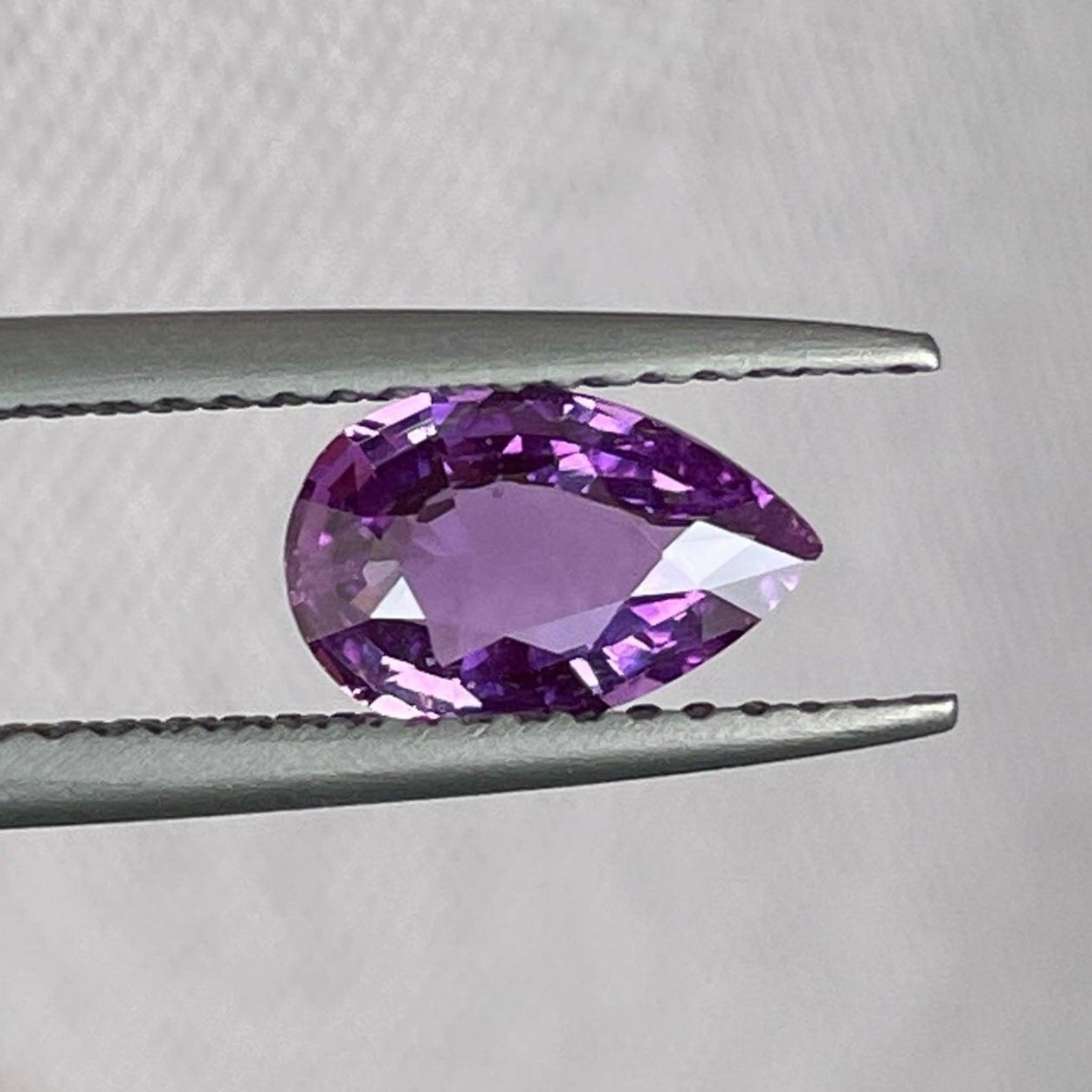 Loose purple pink sapphire gemstone, 1.08 carats, natural pink sapphire for jewelry, displayed on a jewelry stand.