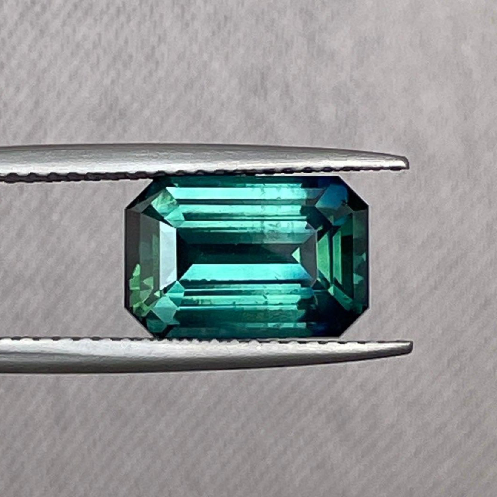Loose teal sapphire with emerald cut, 4.50 carats, from NASHGEMS, showcasing vibrant teal color similar to Montana Yogo sapphires.