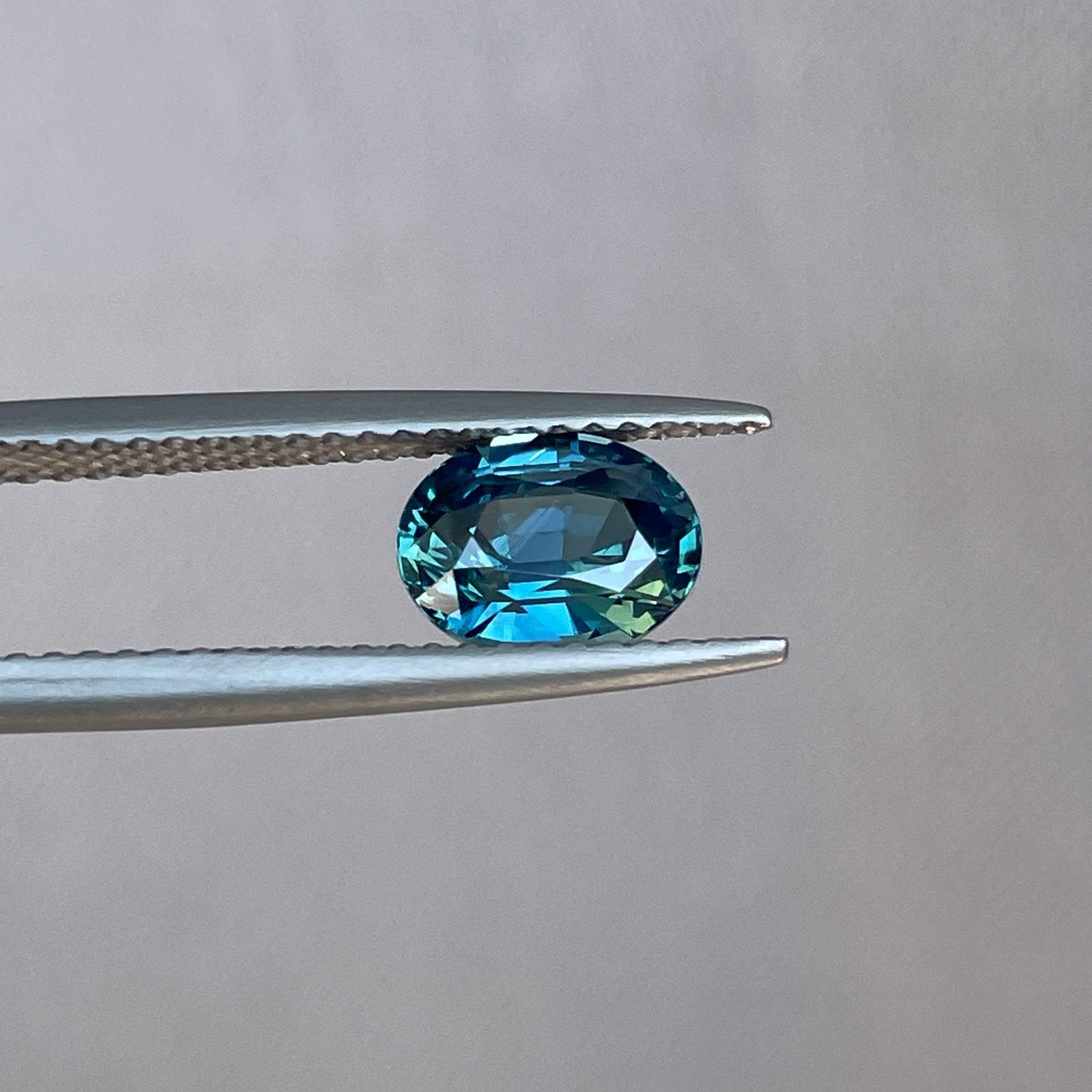 Teal sapphire engagement ring with gold band and gemstones, featuring a 1.60 carat sapphire, from NASHGEMS jewelry collection.
