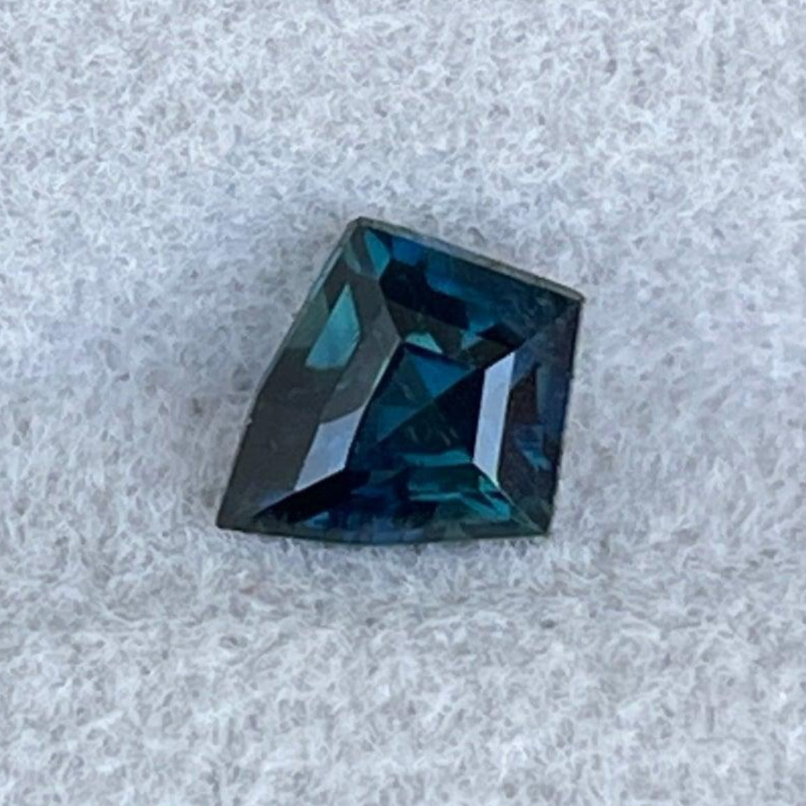 Teal sapphire gemstone weighing 0.82 carats, vibrant blue-green color, from NASHGEMS, close-up view of the polished gem.