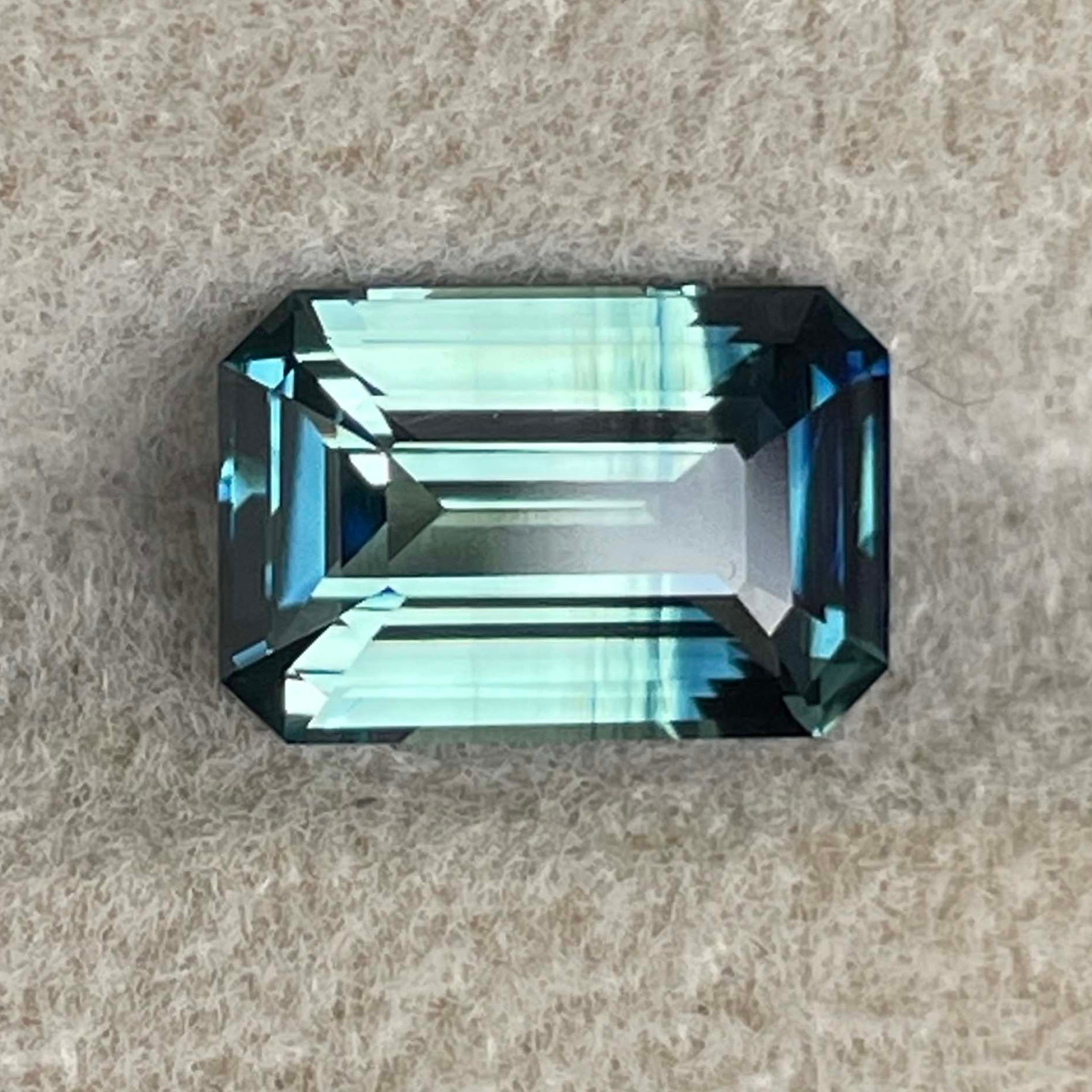 Teal natural bi-color sapphire with 2.07 carats in an emerald cut, showcasing vibrant blue-green hues for engagement jewelry.