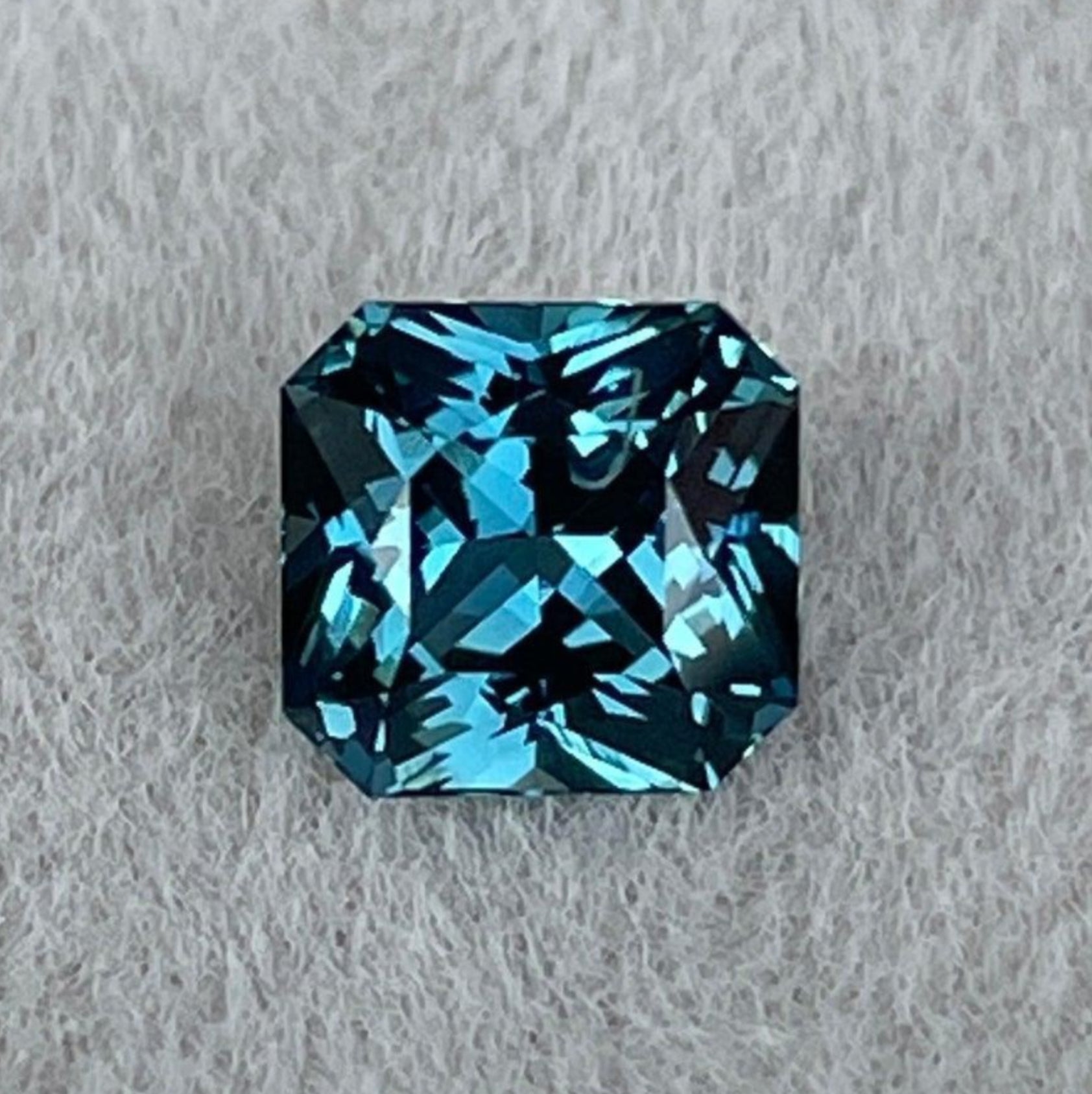 Teal sapphire gemstone with radiant cut, blue-green color, from Madagascar, displayed for custom ring design by NASHGEMS.