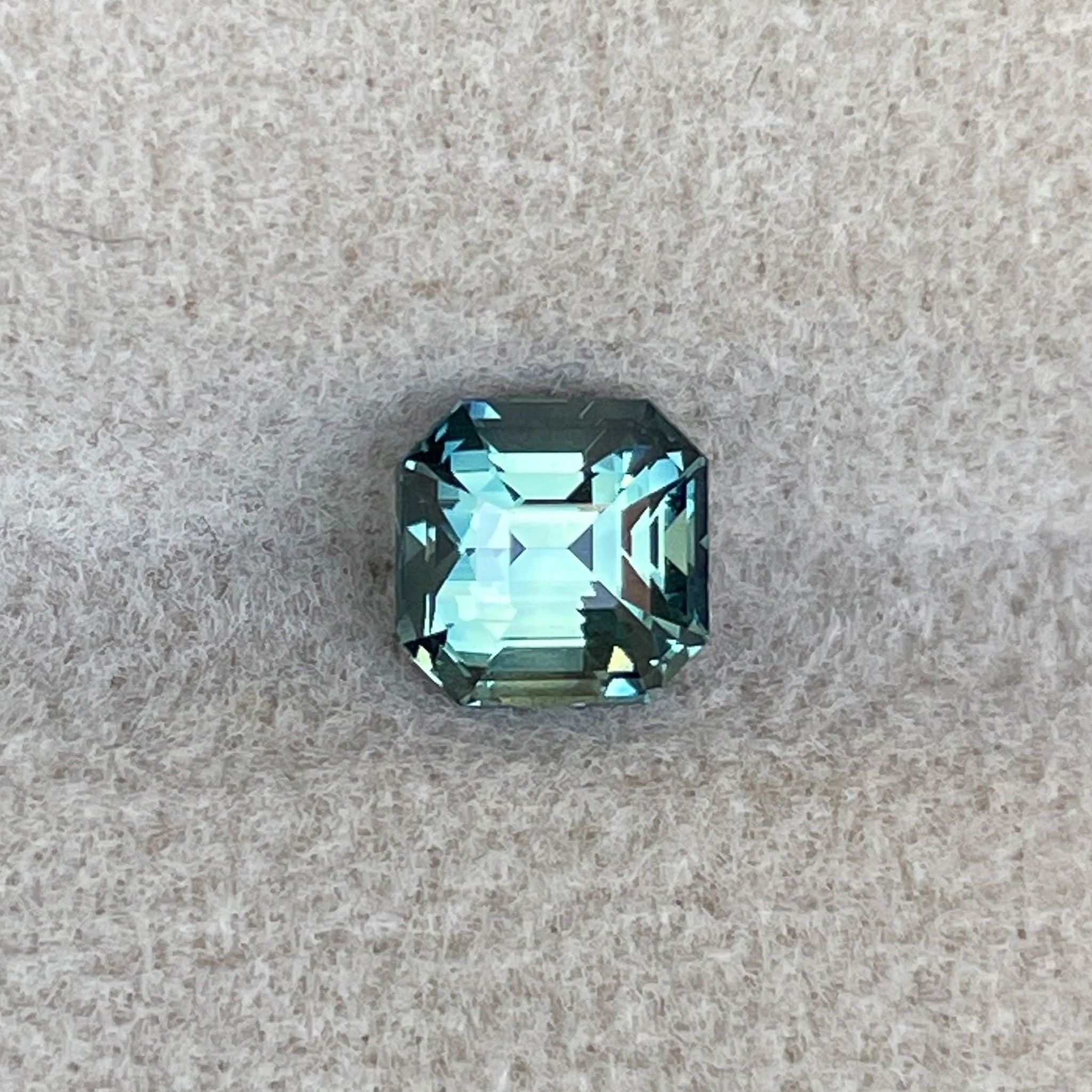Natural teal green sapphire, 1.36 Ct emerald cut, loose gemstone from NASHGEMS, ideal for engagement rings or custom jewelry.