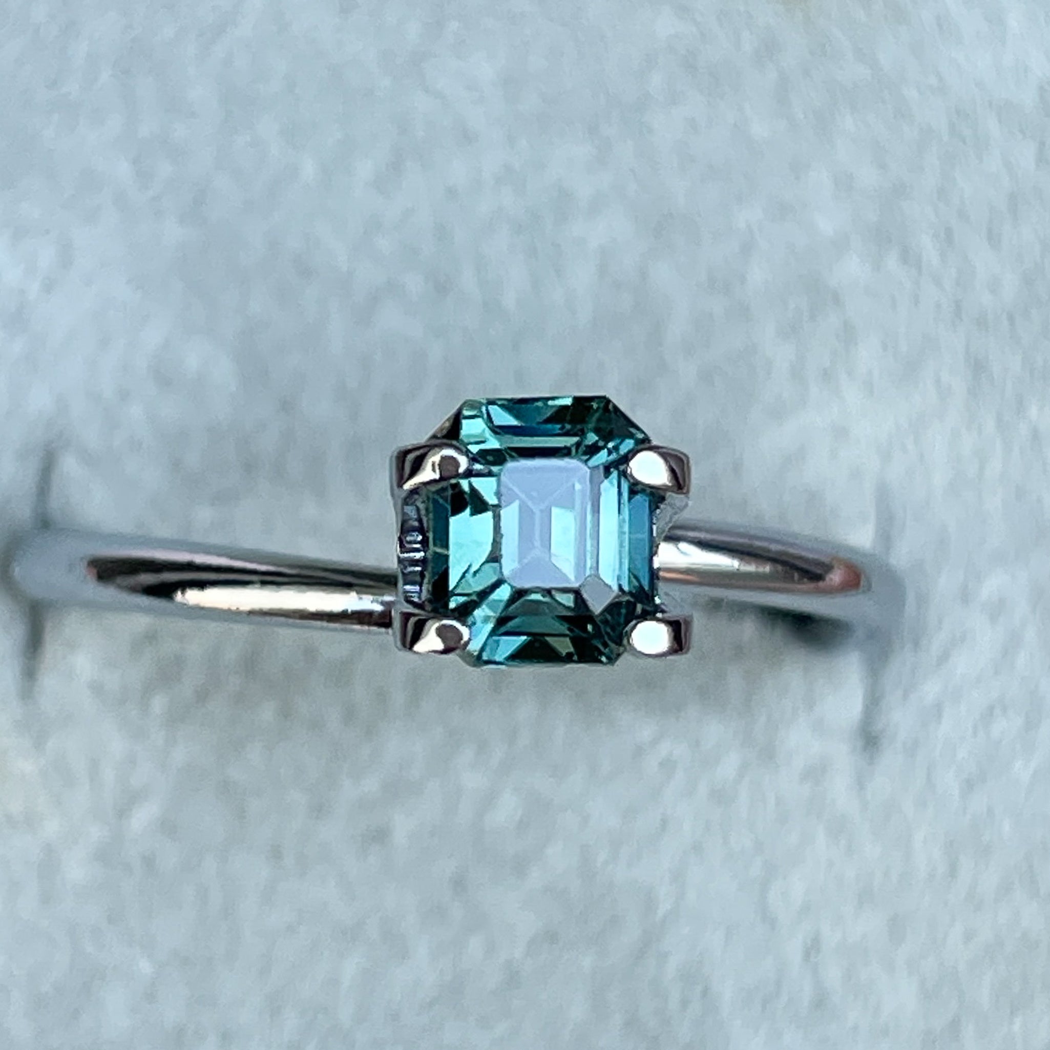 Natural teal sapphire loose stone, 1.05 Ct emerald cut, from NASHGEMS, showcasing vibrant blue-green hues for jewelry or engagement.