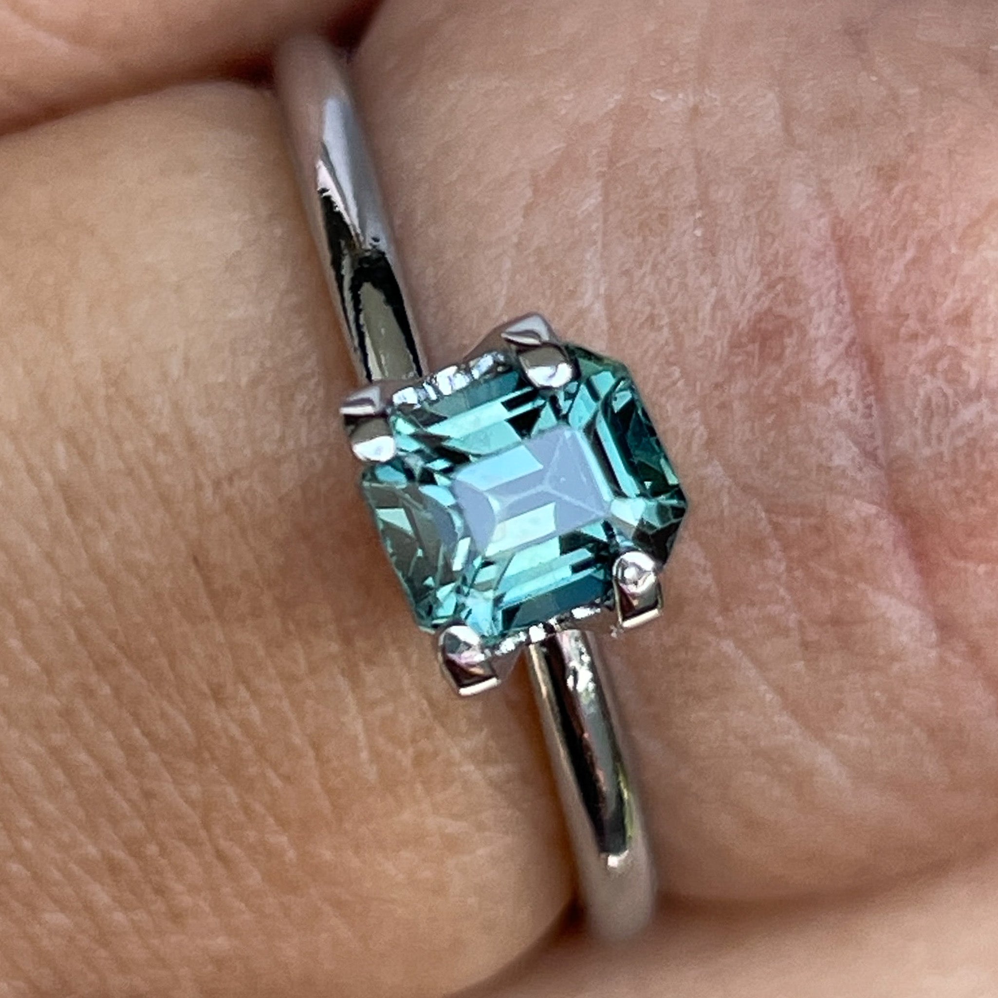 Natural NASHGEMS teal sapphire, 1.05 ct emerald cut loose gemstone in blue-green hues, ideal for jewelry or engagement rings.