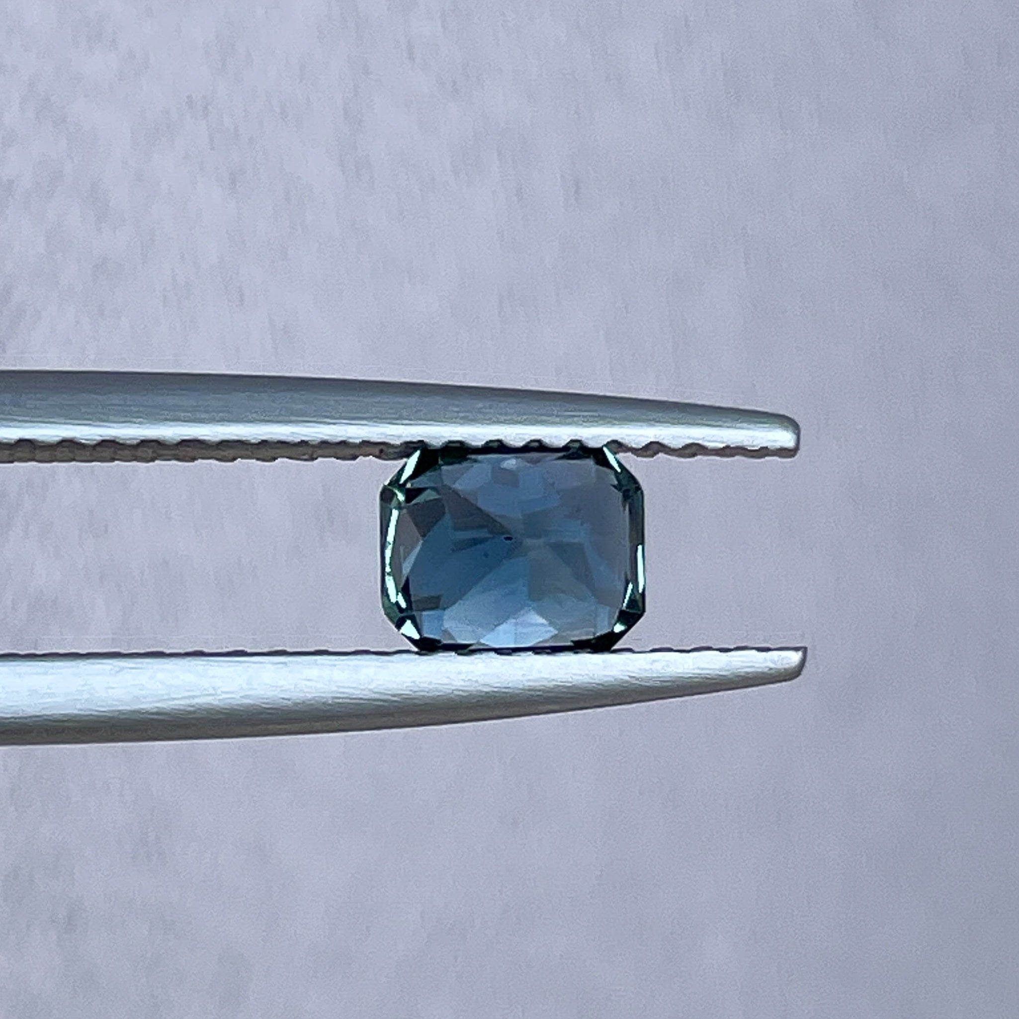 Natural teal blue sapphire 0.98 Ct radiant cut by NASHGEMS, showing the vibrant color and clarity of this loose gemstone.