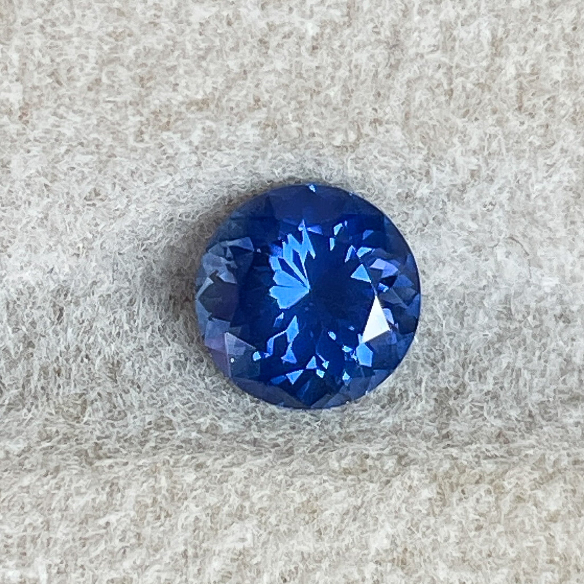 Natural round-cut Ceylon blue sapphire displaying vivid royal blue colour on a white background.