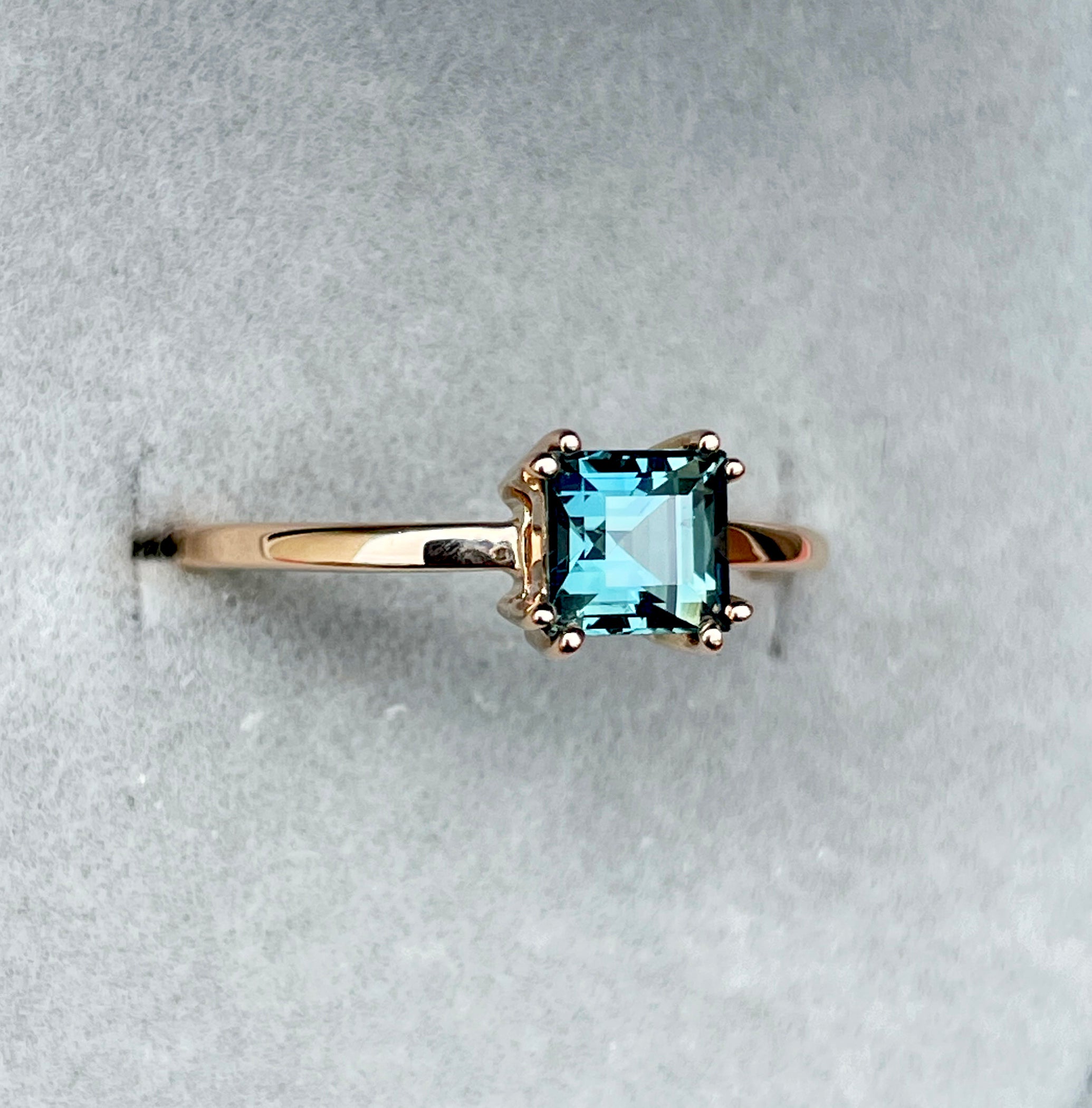 elegant ring features a 1.00 crt  Natural Teal Sapphire surrounded by sparkling CONFLICT-FREE natural white sapphire set in a solid 18k Rose Gold ring setting. The timeless and classic design of this ring will make your engagement unforgettable.