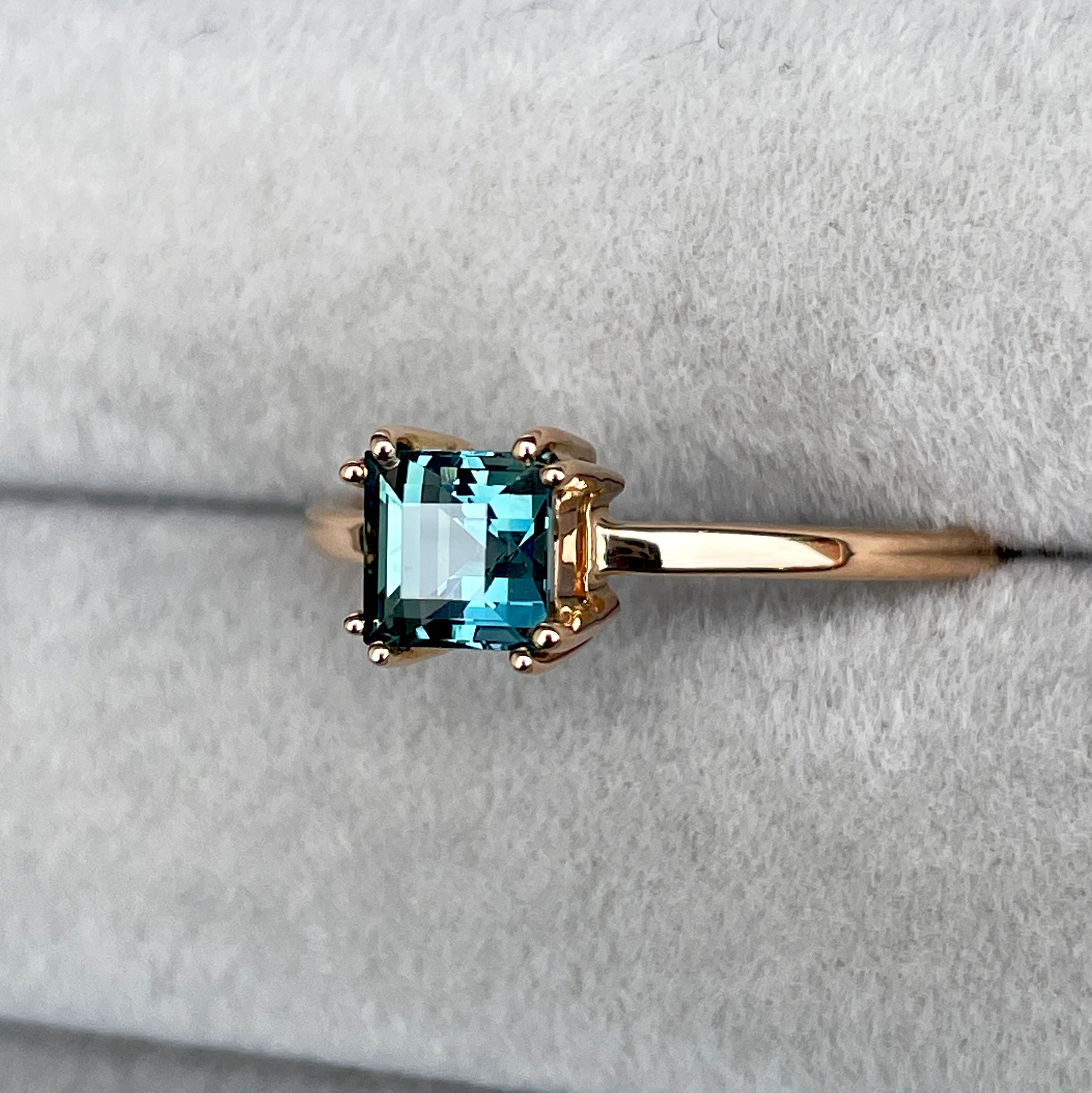 elegant ring features a 1.00 crt  Natural Teal Sapphire surrounded by sparkling CONFLICT-FREE natural white sapphire set in a solid 18k Rose Gold ring setting. The timeless and classic design of this ring will make your engagement unforgettable.