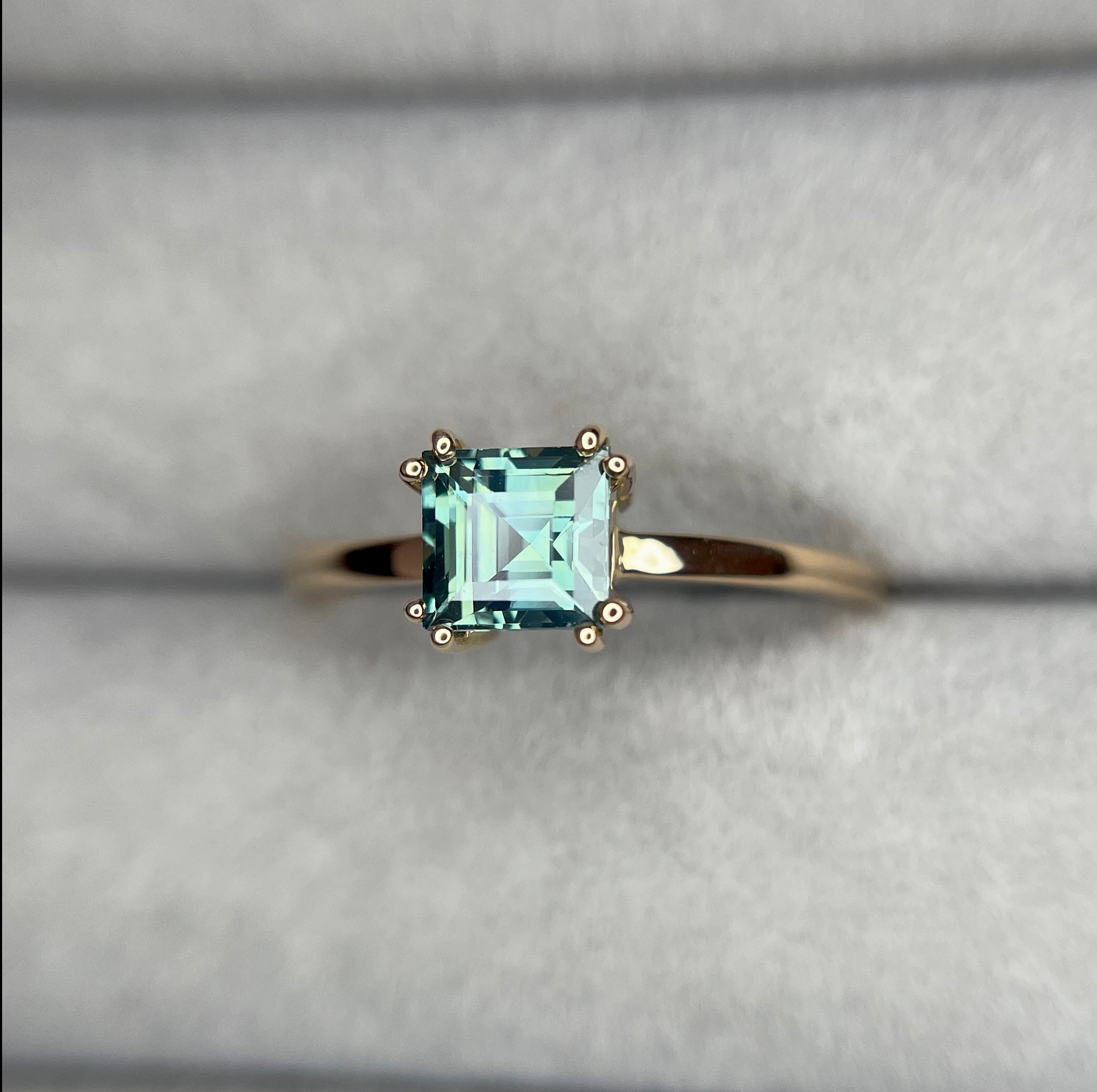 elegant ring features a 1.00 crt  Natural Teal Sapphire surrounded by sparkling CONFLICT-FREE natural white sapphire set in a solid 18k Rose Gold ring setting. The timeless and classic design of this ring will make your engagement unforgettable.