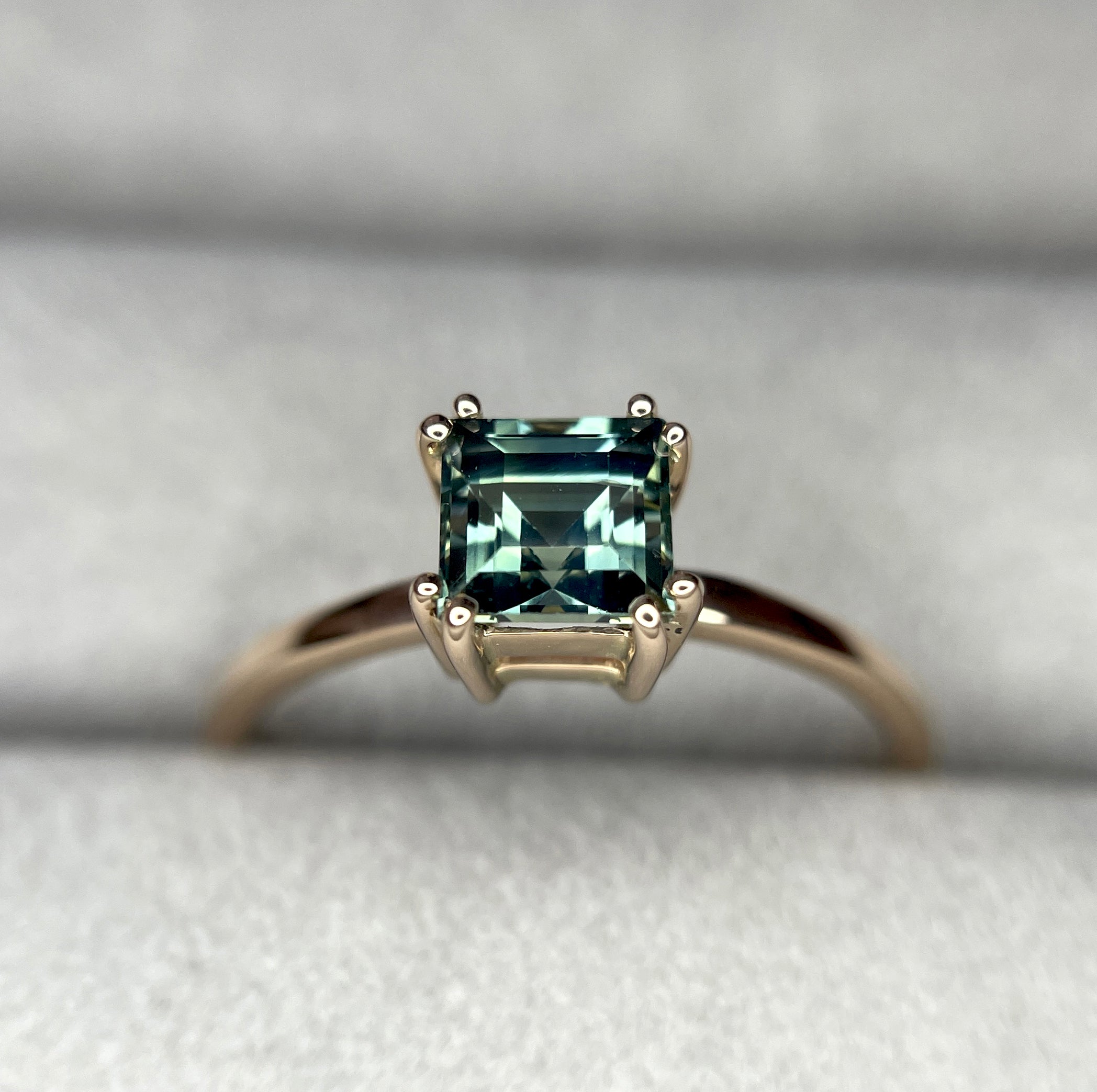 elegant ring features a 1.00 crt  Natural Teal Sapphire surrounded by sparkling CONFLICT-FREE natural white sapphire set in a solid 18k Rose Gold ring setting. The timeless and classic design of this ring will make your engagement unforgettable.