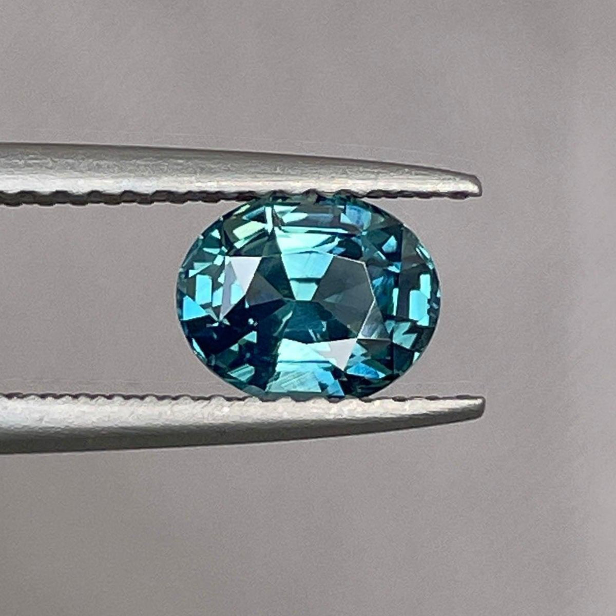 Blue-green oval-shaped sapphire gemstone from NASHGEMS, 1.23 carats, ideal for custom jewelry like rings and pendants.