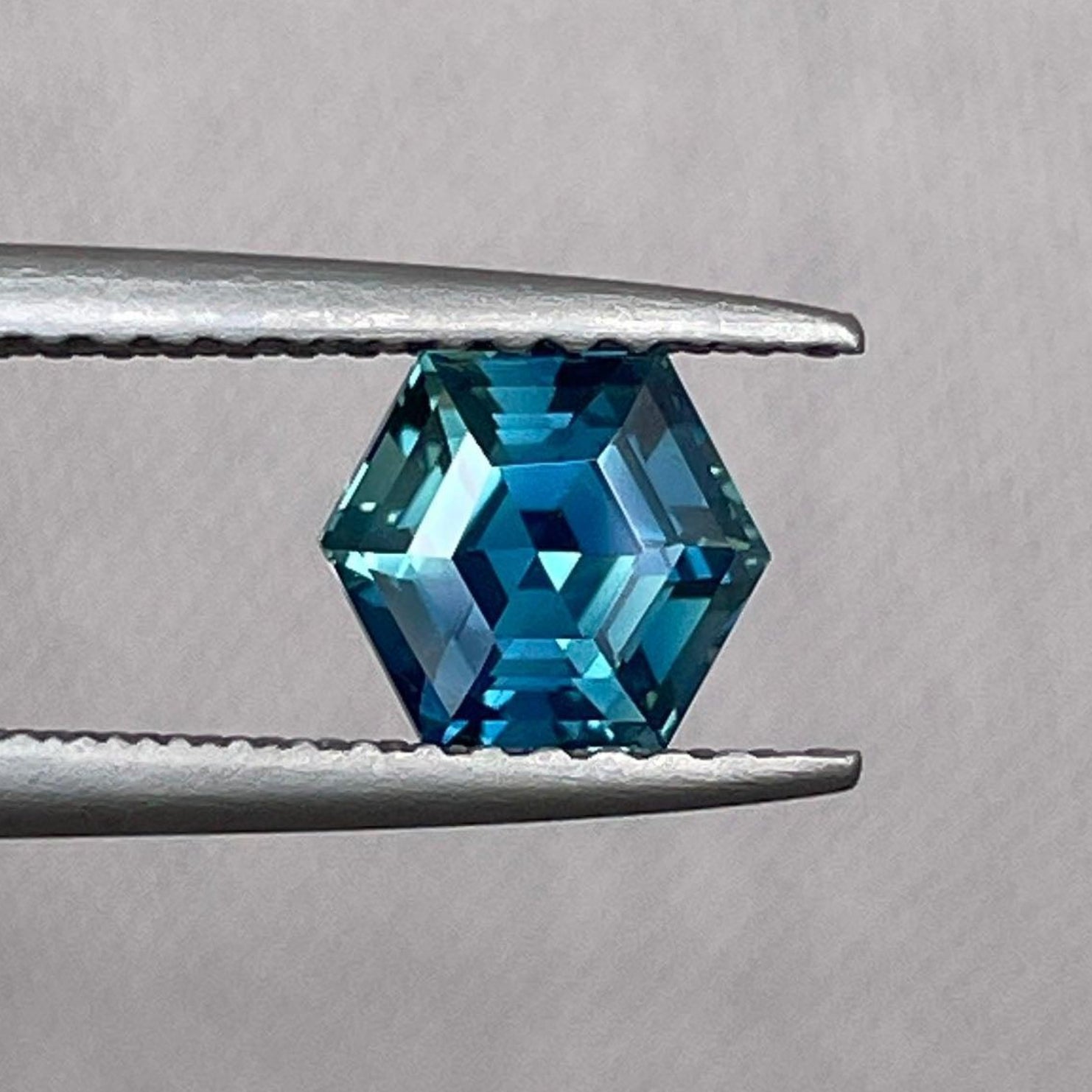 Teal blue-green sapphire hexagon-shaped loose gemstone, 1.24 crt, for jewelry making, featuring vibrant color and polished surface.