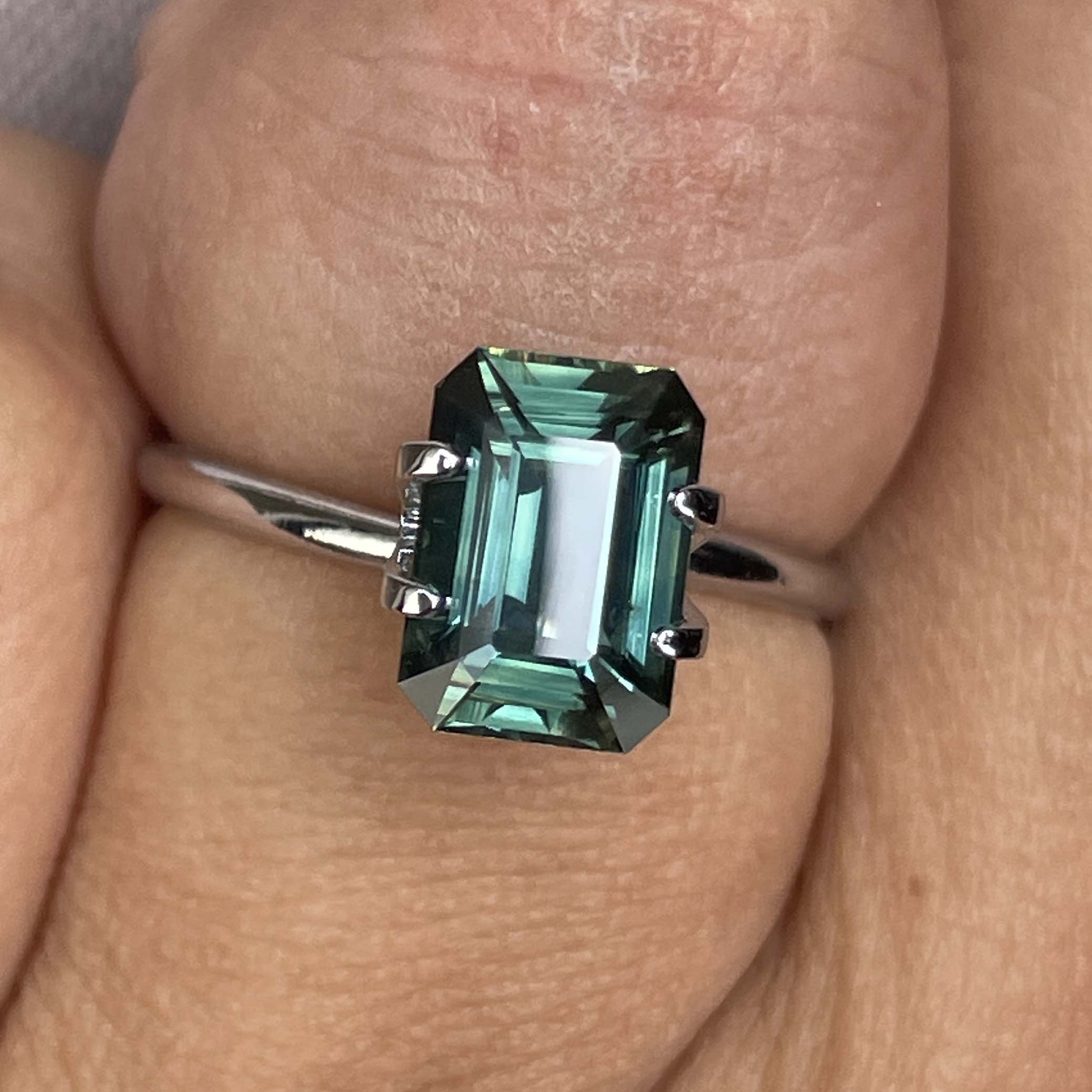 Natural green sapphire 3.03 Ct emerald cut loose gemstone by NASHGEMS, showcasing vibrant teal color and clear gemstone detail.