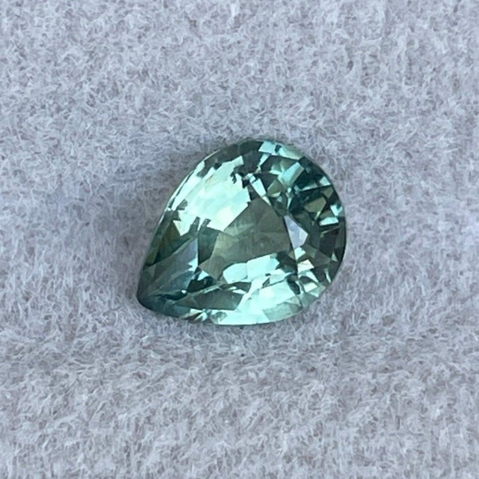 Natural green sapphire gemstone from NASHGEMS, 0.89 ct. pear cut teal sapphire with dark and light mint and olive green hues.