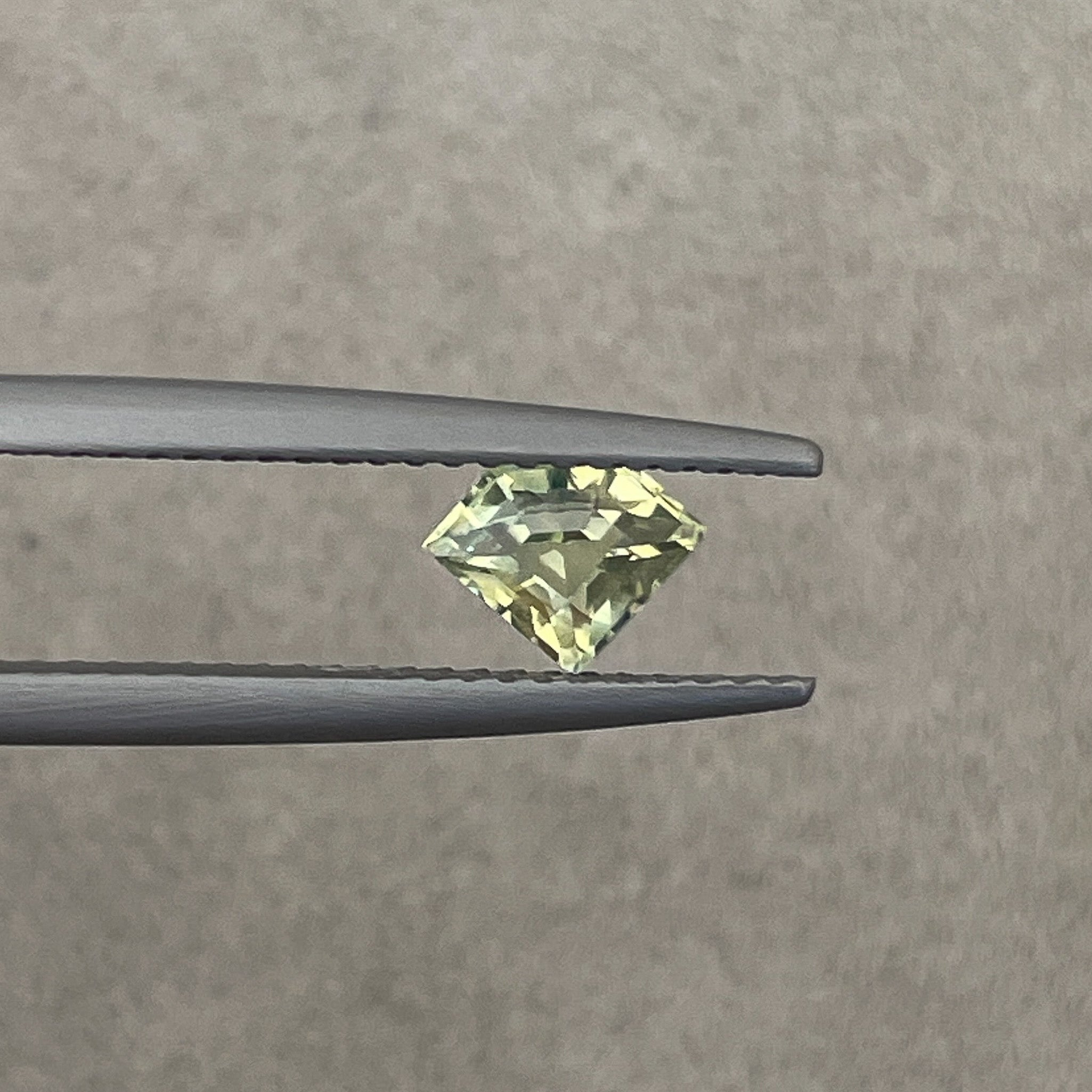Natural pale green-yellow teal sapphire, 0.72 Ct shield cut loose gemstone by NASHGEMS for engagement or custom jewelry.