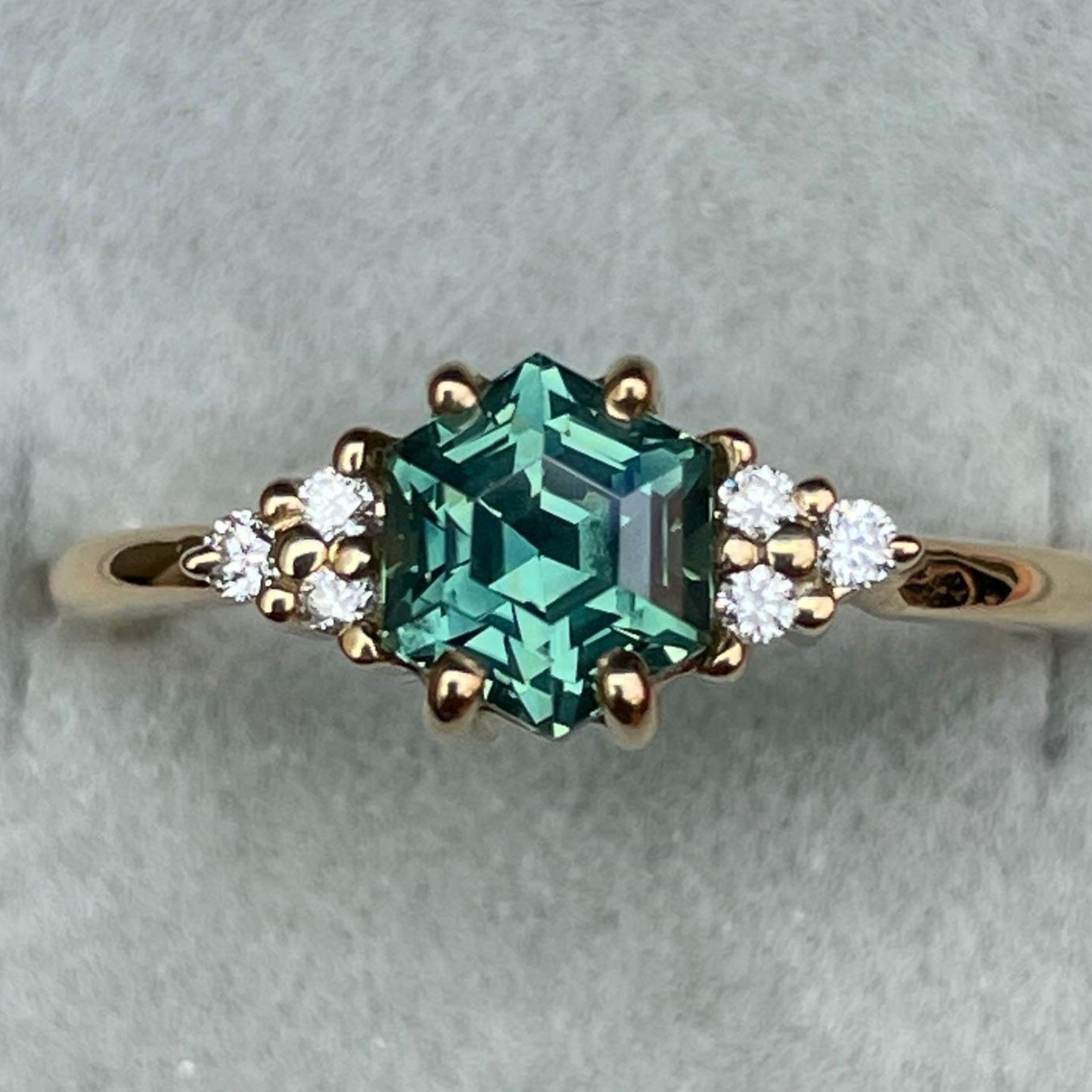 Teal sapphire ring by NASHGEMS with 1.33 ct hexagon cut sapphire and diamond accents in rose gold setting.