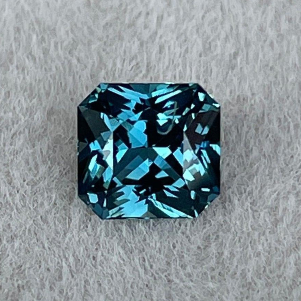 Teal sapphire gemstone with radiant cut, blue-green color, from Madagascar, displayed for custom ring design by NASHGEMS.