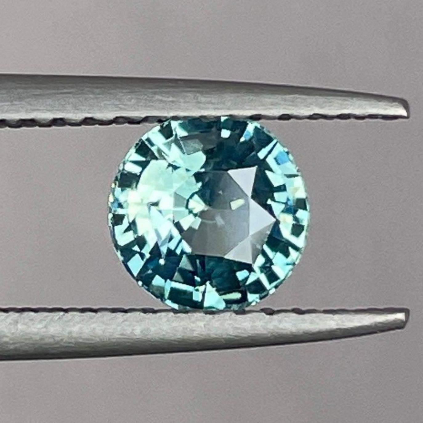 Well-cut 0.96 ct teal sapphire from NASHGEMS showing vibrant color and lustrous finish, highlighting the gemstone's blend and clarity.