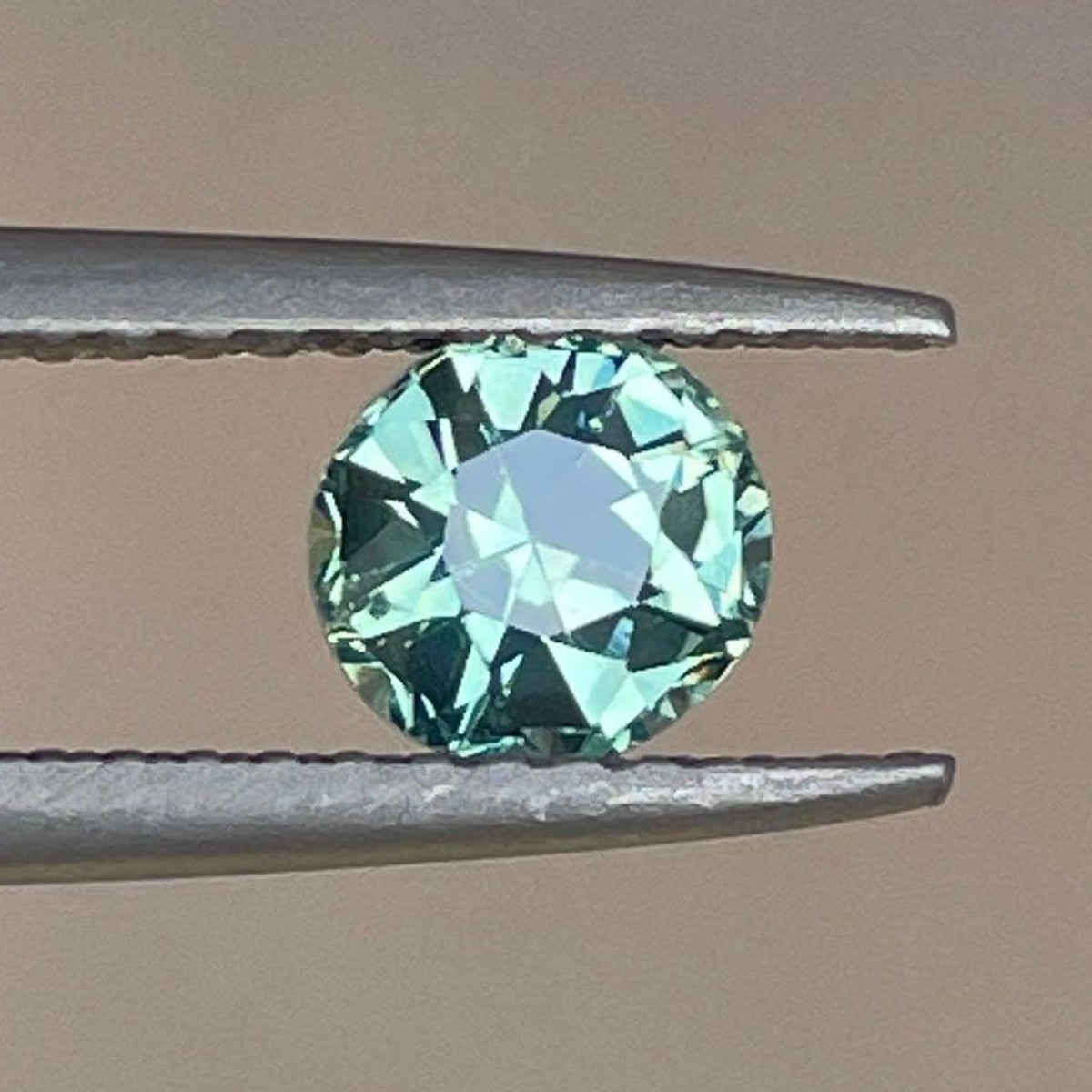 Teal green sapphire 0.89 carats from NASHGEMS showcasing a vibrant, faceted gemstone with a rich green hue.