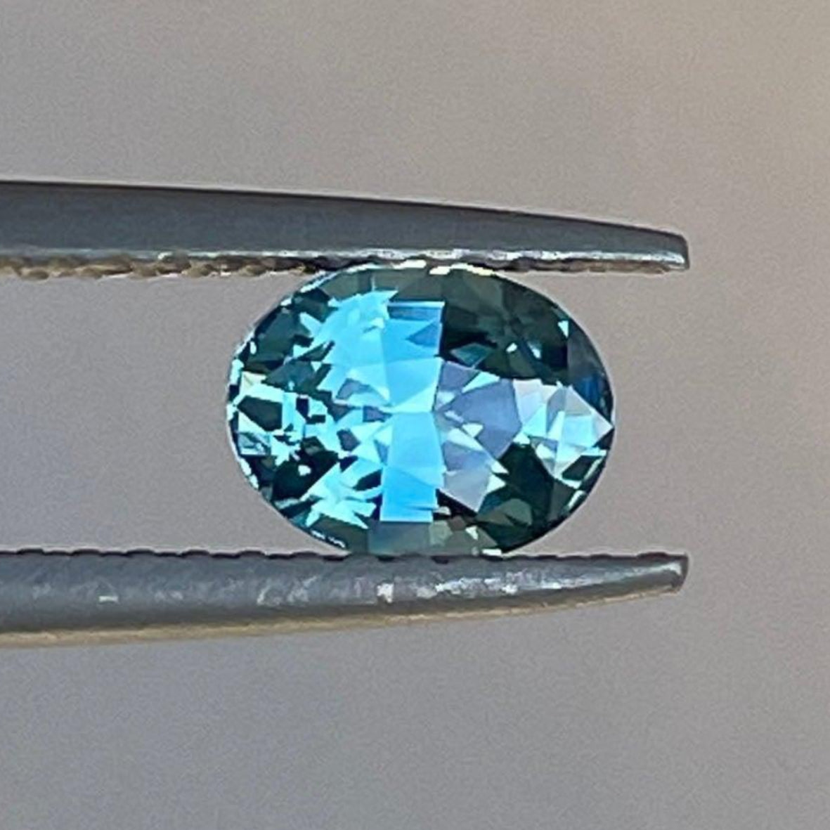 حجر الياقوت الأزرق المخضر من NASHGEMS، ياقوت أزرق مخضر كاريبي، وزن 0.97 قيراط، بسطح أملس وملمّع ولون حيوي.