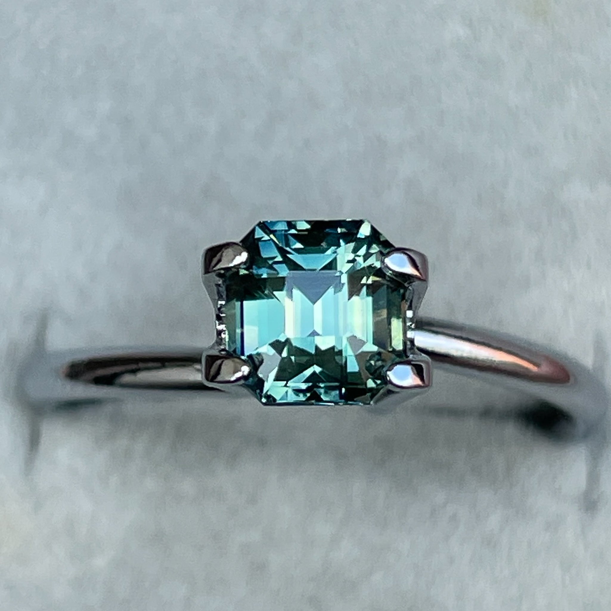 Natural teal green sapphire 1.36 Ct emerald cut, loose gemstone from NASHGEMS, ideal for engagement rings or custom jewelry.