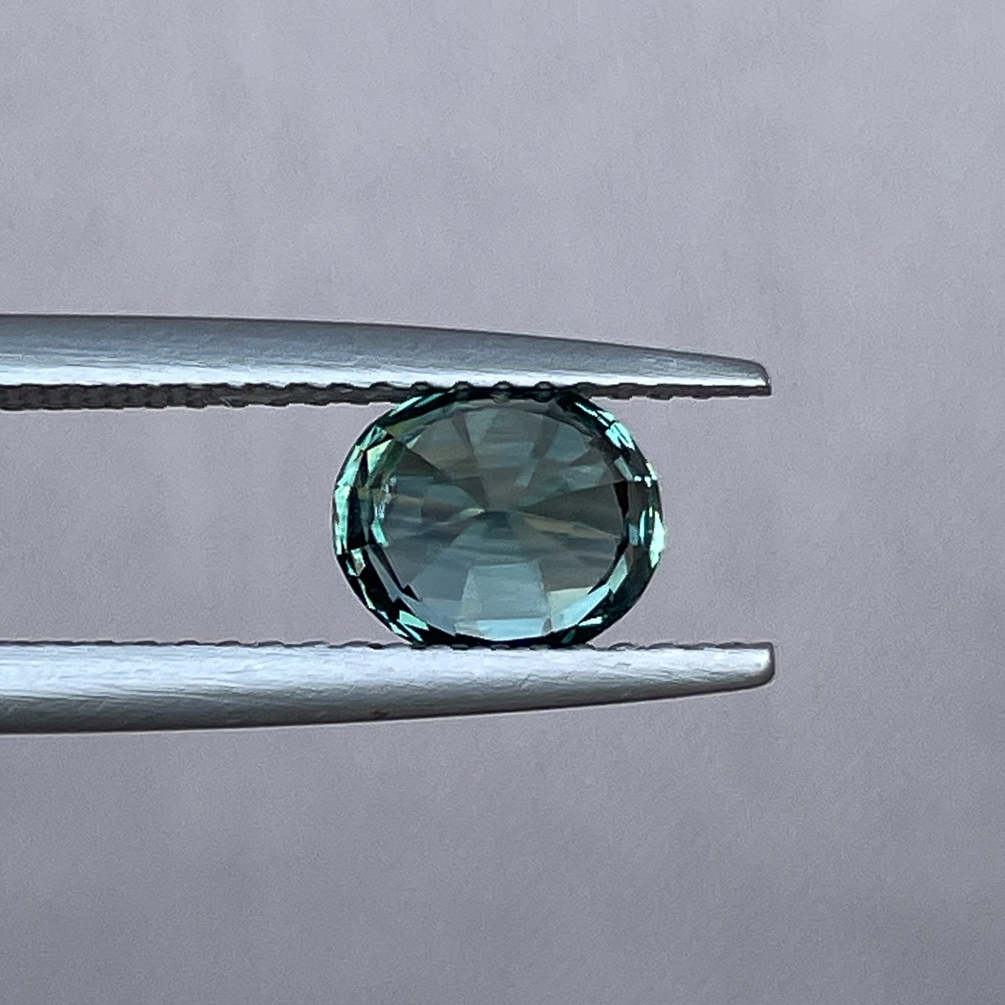 Teal blue-green NASHGEMS natural sapphire loose gemstone, 1.56 Ct oval cut for jewelry or engagement ring design.
