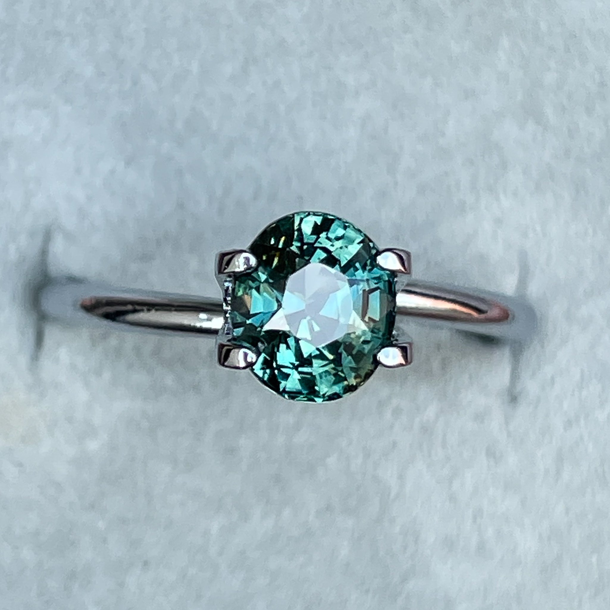 Natural teal sapphire loose gemstone, 1.56 Ct oval cut by NASHGEMS, vibrant blue-green color for jewelry or engagement rings.