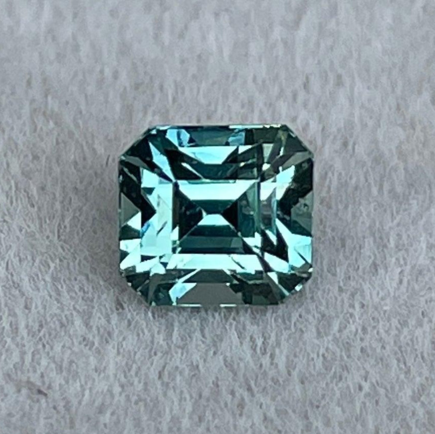 Saphir teal taille asscher, 1,03 ct, serti dans une bague de mariage ou d'anniversaire en or blanc par NASHGEMS, mettant en valeur sa teinte émeraude bleu-vert.
